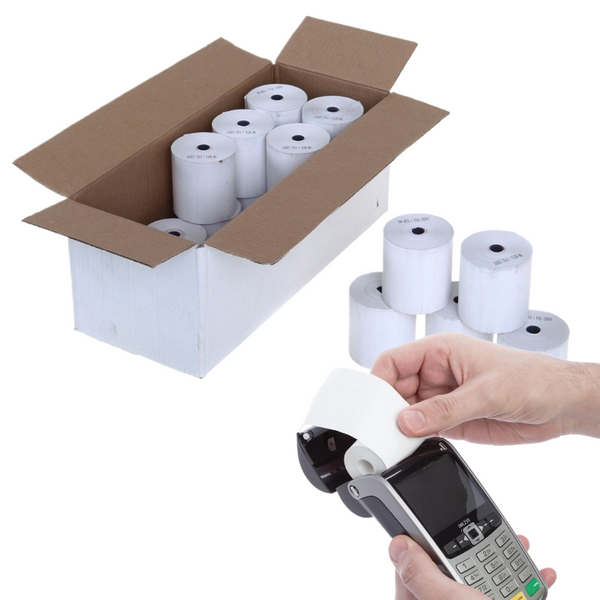 White thermal receipt paper rolls shown in an open cardboard box, with several loose rolls beside a hand holding one roll over a handheld payment terminal. A pair of hands is visible, so this is classified as Lifestyle.