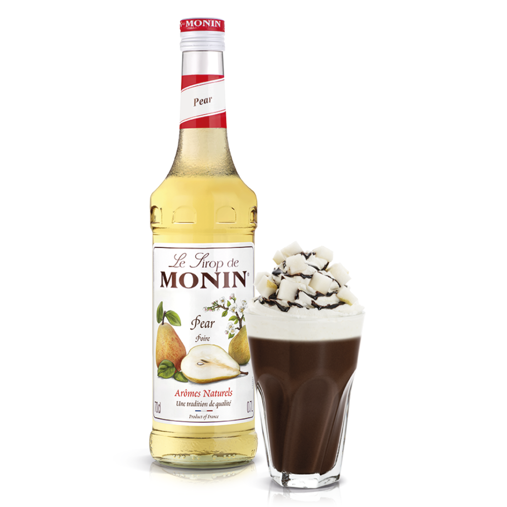 A glass bottle of Monin pear syrup 700ml stands next to a tall glass filled with a dark coffee drink topped with whipped cream and chocolate shavings on a white background. Discount Coffee