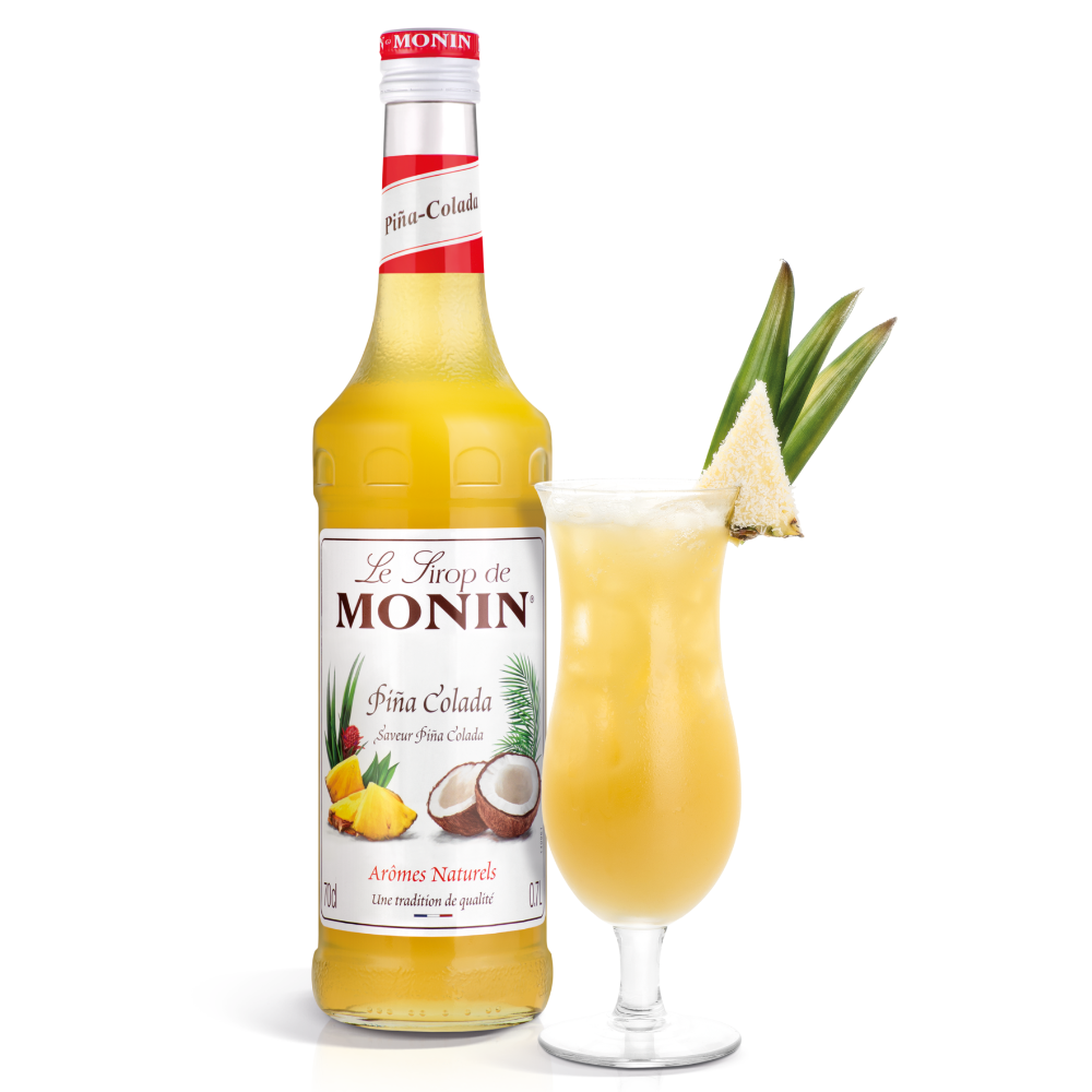 Monin Pina Colada Syrup Bottle 70 cl. A picture of a tall glass of Pina Colada, Puerto Rico's iconic national drink next to a bottle of Monin Pina Colada Syrup on a white background - Discount Coffee